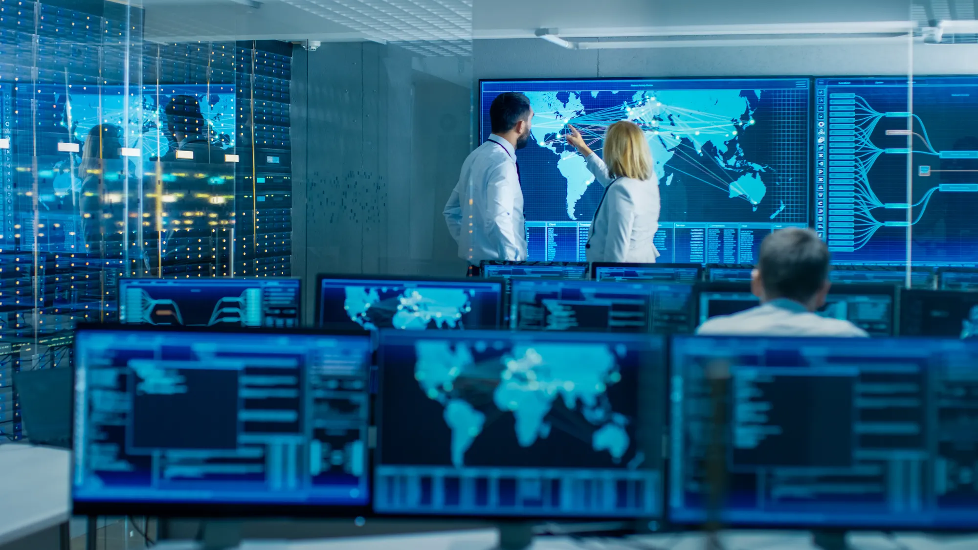 Two professionals analyzing global data in a high-tech control room.