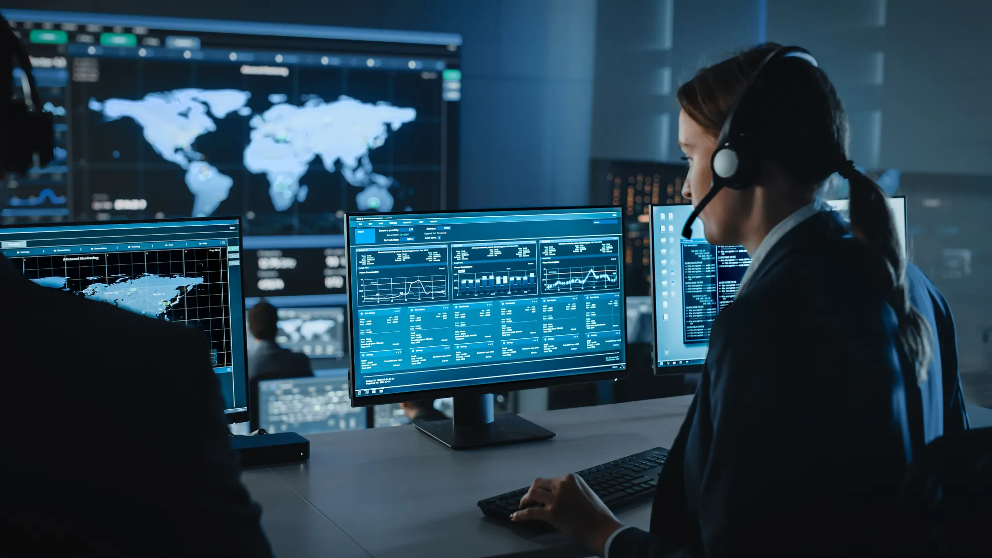 Professionals in a high-tech control room monitoring global data and analytics across multiple screens.